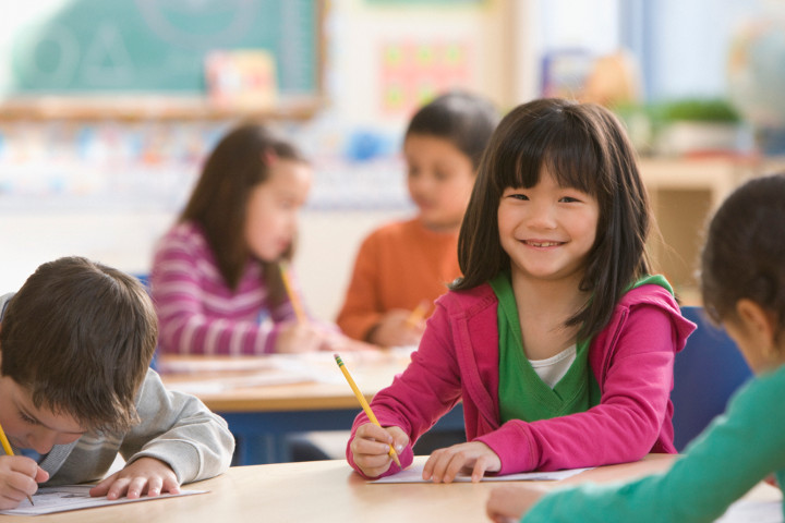 Smiling girl in classroom writing